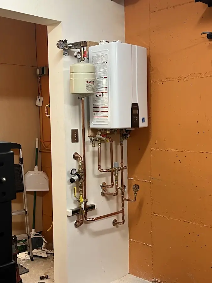 Plumbing technician inspecting water heater connections in North Manheim
